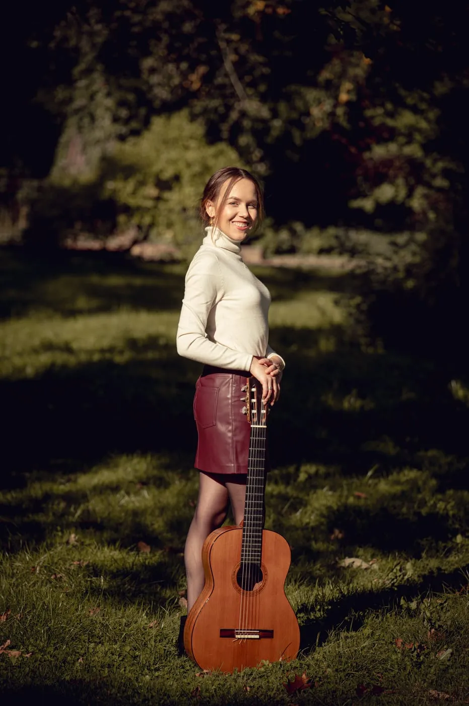 Margaréta Lakner standing with her guitar in a park